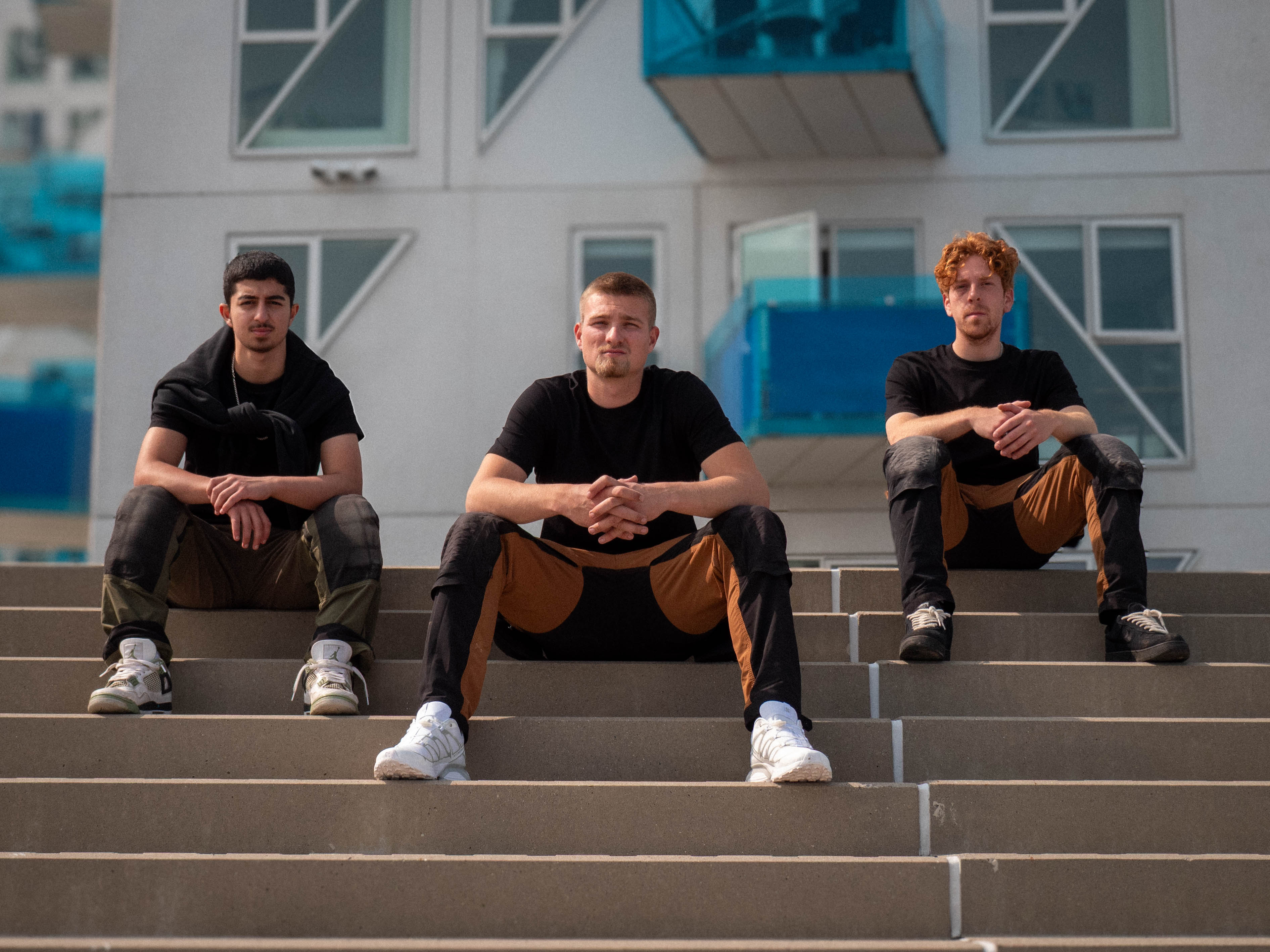 Tre fra holdet siddende på en udendørs trappe